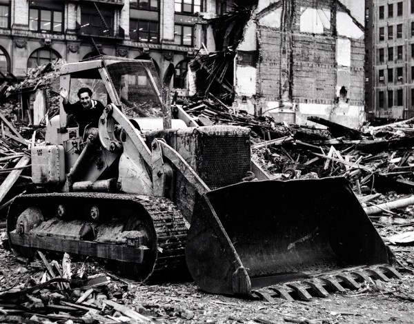 A black-and-white photo of artist Frank Stella sitting in the cab of a bulldozer