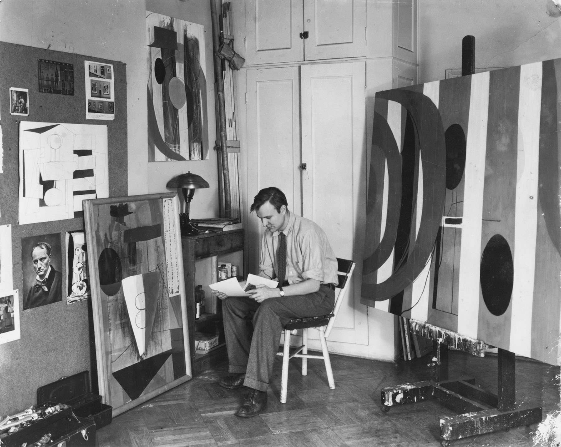 A black-and-white photograph of artist Robert Motherwell in his studio