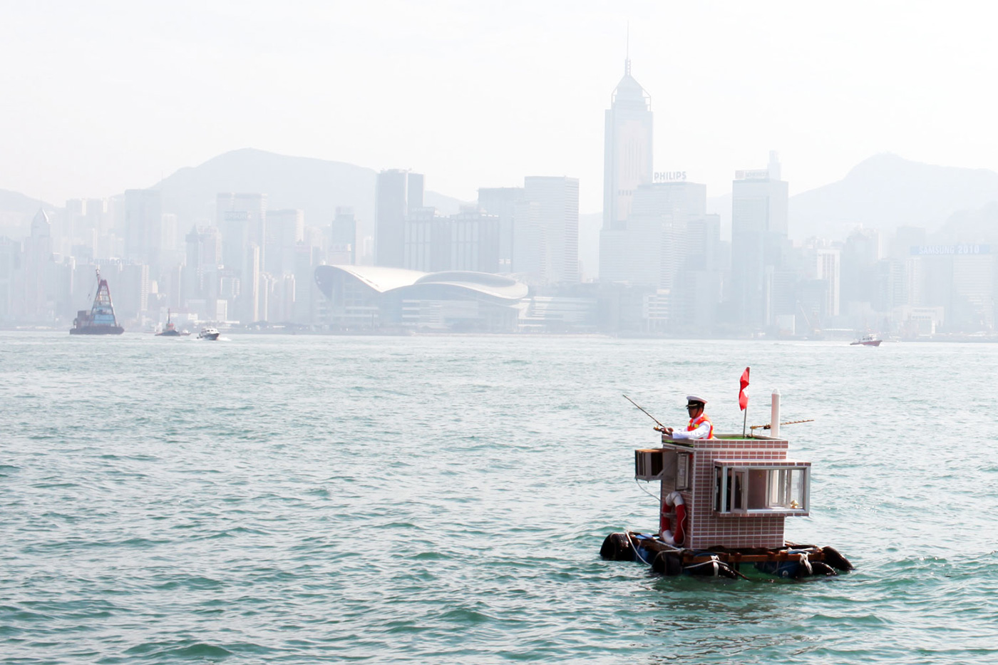 A photograph of a person floating on a raft in front of the Hong Kong skyline