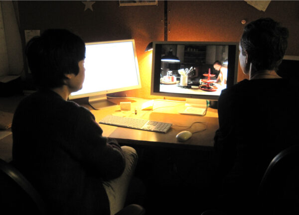 A photo of two people sitting in front of a computer screen