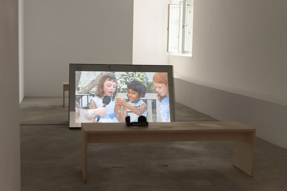 Alt Text: photo of a video art installation showing a group of children being interviewed.