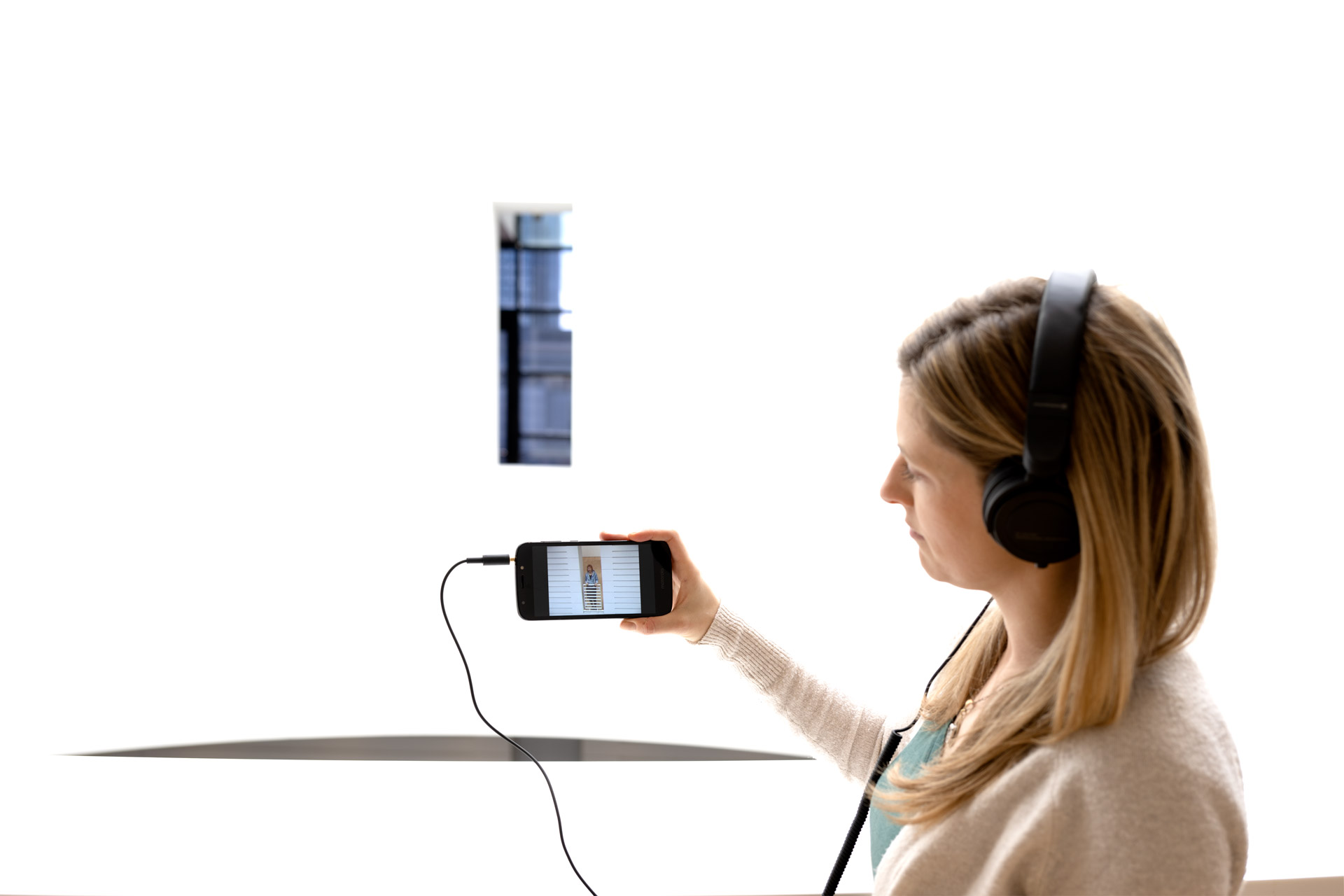 Photo of a person wearing headphones holding up a smartphone screen