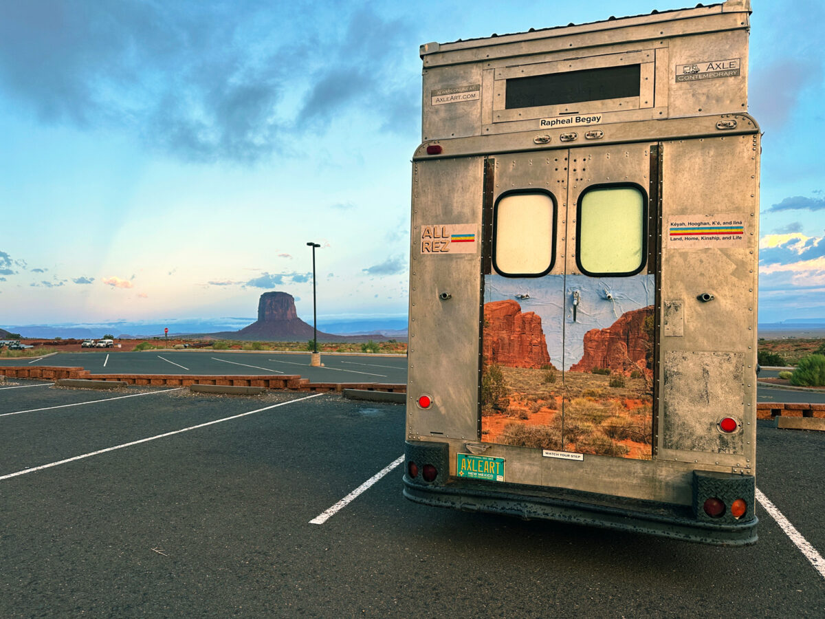 A stepvan parked in a parking lot surrounded by desert landscape