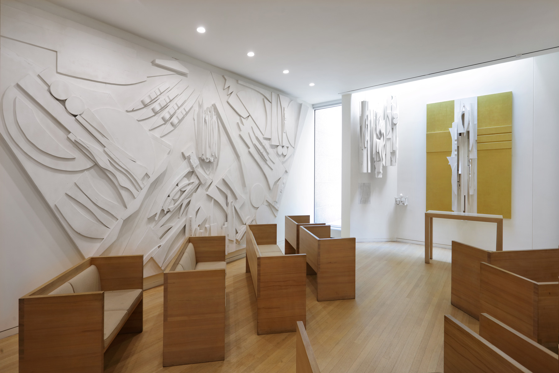 A room with large-scale artworks on the walls and wooden benches