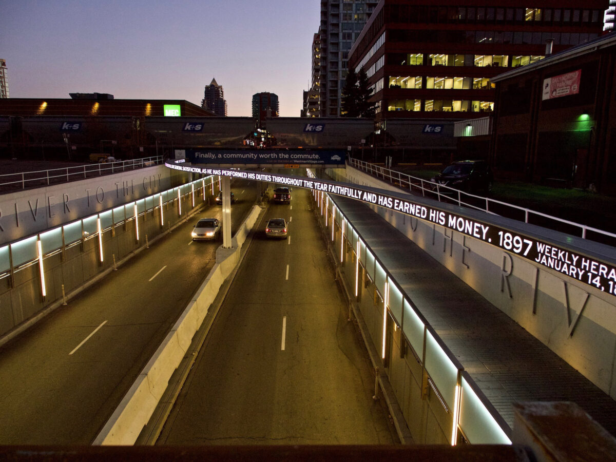 A city highway at dusk with buildings in the distance