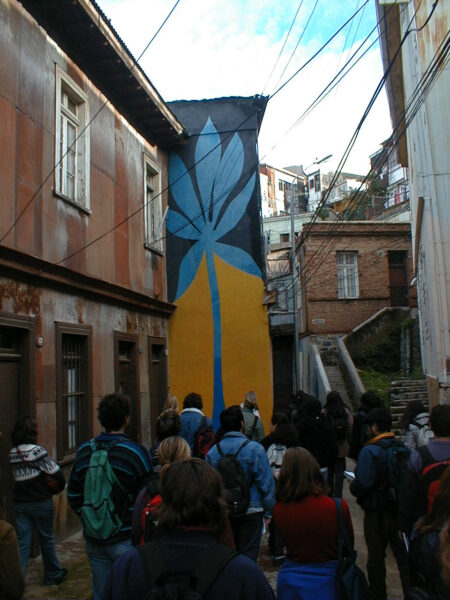 A group of people viewing a tall outdoor mural of a flower