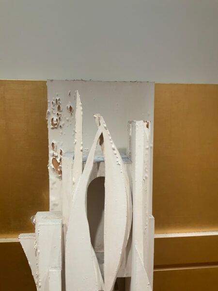 A detail image of a sculptural artwork with peeling white paint