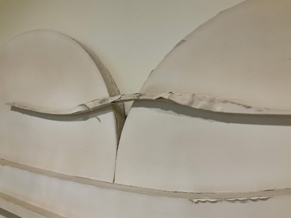 A close-up of a sculptural artwork with peeling white paint